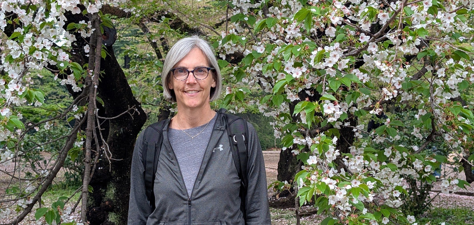Jen Shenberger smiling under a blossoming tree